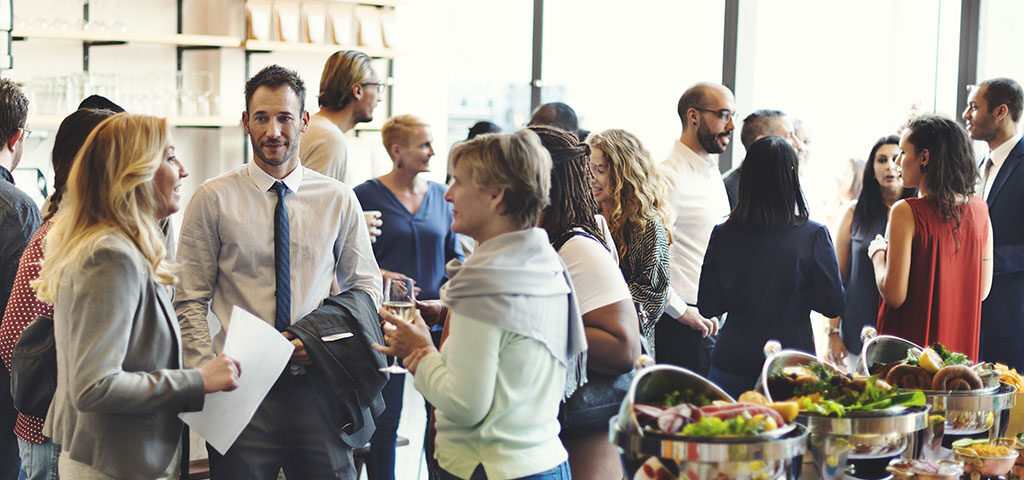 Ein Catering in Neubrandenburg bei einer Frimenfeier: Mitarbeiter stehen am Büffet und unterhalten sich bei gutem Essen.